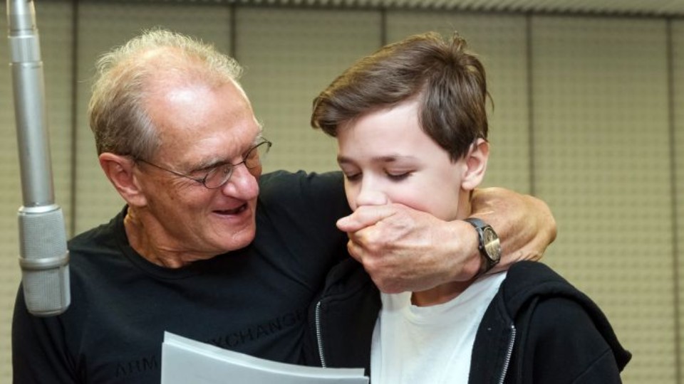 Schauspieler Joachim Kaps hält dem Sprecherkind Jeremy Kindel vor dem Mikrofon den Mund zu | © rbb/Oliver Ziebe