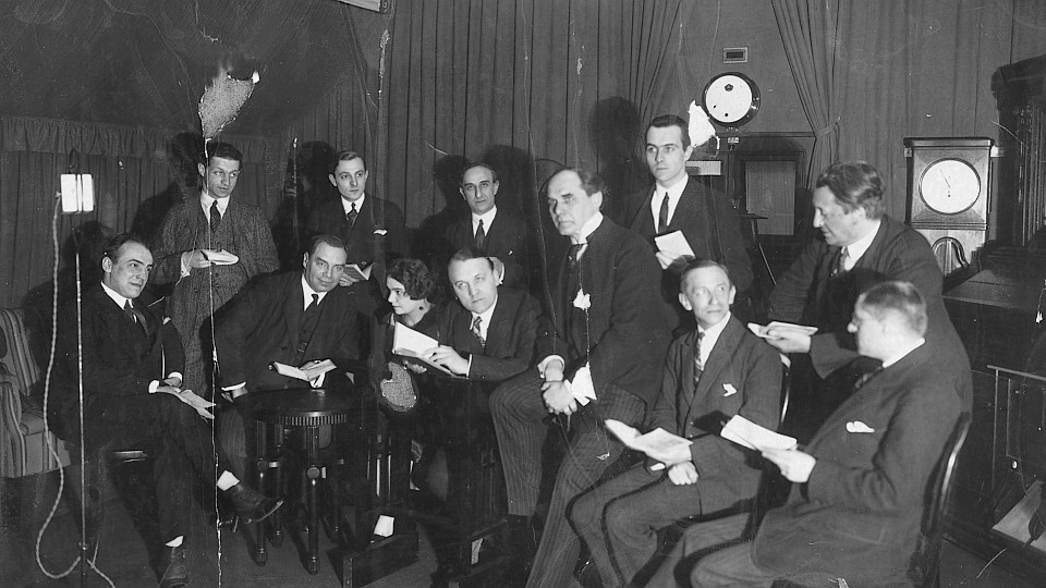 Sprecherensemble im Voxhaus Berlin am 28.03.1925 zur Aufnahme von "Die Räuber" vor Mikrofon; u.a. Alfred Braun (4.v.l. unten), Ilse Hartleb-Hagedorn (3.v.l. unten) und Karl Zander (1.v.l.unten) | © Deutsches Rundfunkarchiv/August Scherl